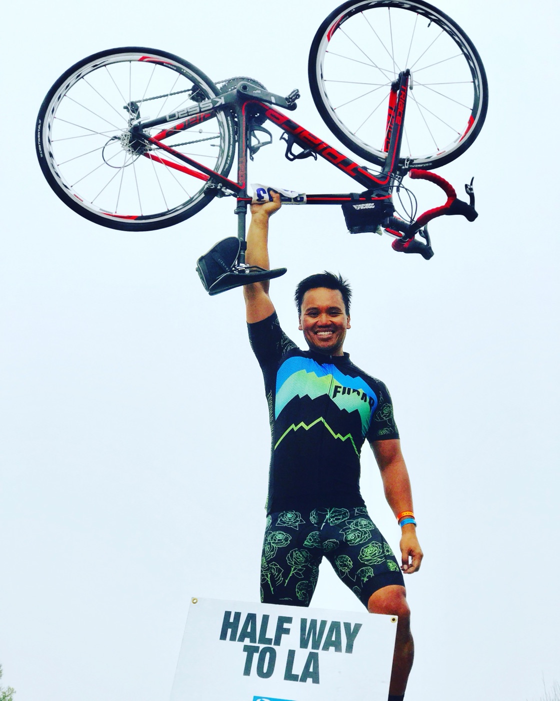 Dr. Ken Ycmat holding his road bike overhead at a California AIDS/LifeCycle rest stop