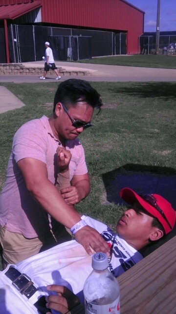 Dr. Ken Ycmat treating an athlete's wrist at an outdoor sporting event