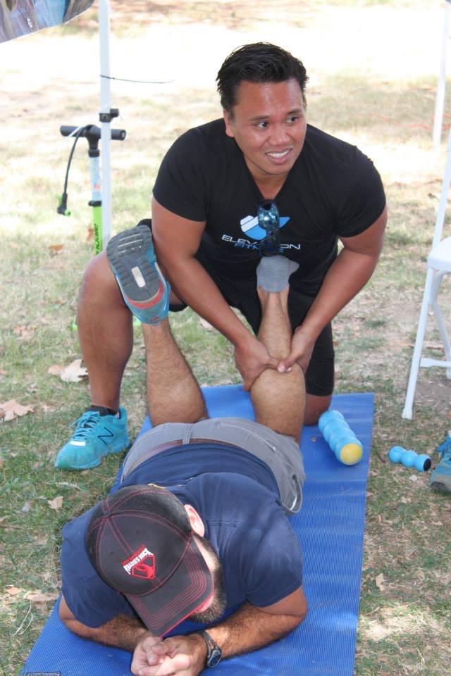 Dr. Ken Ycmat working on an athlete's leg at an outdoor fitness event